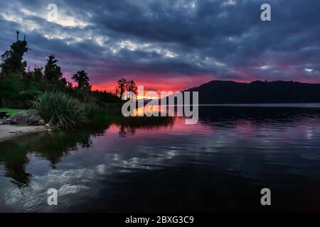 Lago Lantthe, Harihari, Costa Ovest, Nuova Zelanda. Specchio lago paesaggio, bellissimo tramonto. Foto Stock