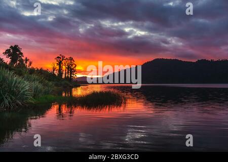 Lago Lantthe, Harihari, Costa Ovest, Nuova Zelanda. Specchio lago paesaggio, bellissimo tramonto. Foto Stock