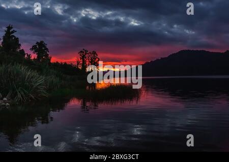 Lago Lantthe, Harihari, Costa Ovest, Nuova Zelanda. Specchio lago paesaggio, bellissimo tramonto. Foto Stock