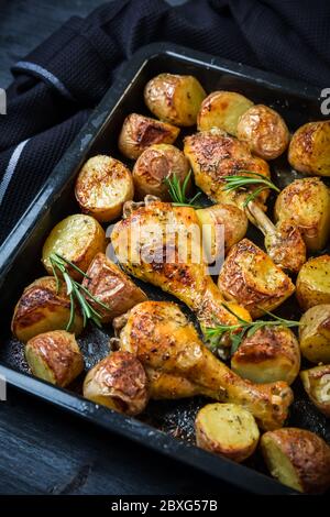 Zampe di pollo calde cotte al forno con patate speziate in teglia su sfondo nero Foto Stock