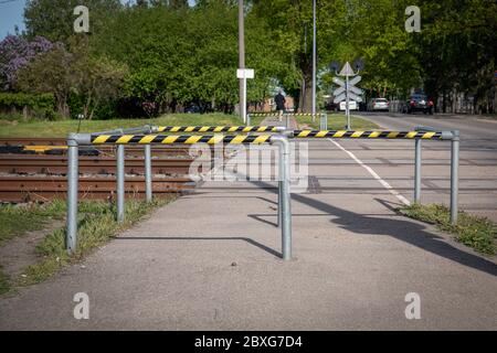 Attraversamento pedonale delle linee ferroviarie. Barriere di sicurezza e nastri di avvertenza. Ambiente urbano e giorno di sole Foto Stock