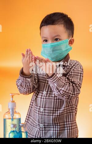 Ragazzo che indossa una maschera chirurgica utilizzando un disinfettante per le mani Foto Stock