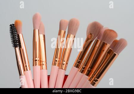 diversi pennelli rosa e oro per il trucco su sfondo chiaro Foto Stock