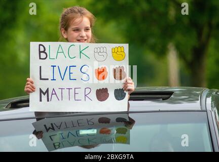 Un bambino tiene un segno durante una veglia di processione di automobile socialmente distante per pagare il rispetto alla morte tragica recente di George Floyd e anche per incoraggiare un Foto Stock