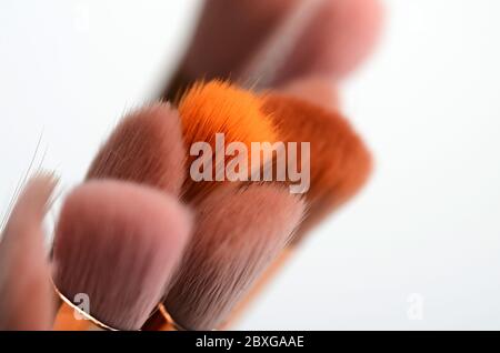 diversi pennelli rosa e oro per il trucco su sfondo chiaro Foto Stock