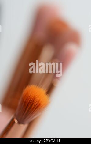 diversi pennelli rosa e oro per il trucco su sfondo chiaro Foto Stock