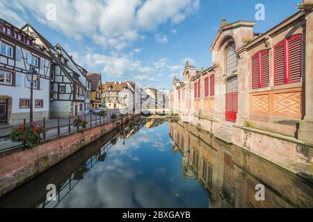 COLMAR, FRANCIA - 30 LUGLIO 2016: Vista di edifici colorati incorniciati in legno e parte del Marché couvert de Colmar al mattino. I riflessi possono essere s Foto Stock