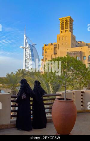 Deux donne vestite di abiti tradizionali guardando Madinat Jumeirah e Burj-El-Arab nel distretto di Jumeirah a Dubai Foto Stock