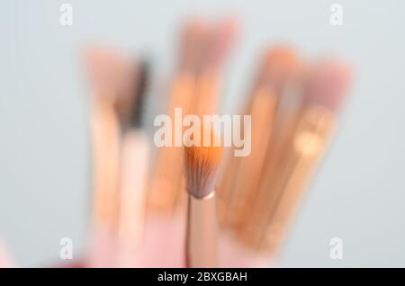 diversi pennelli rosa e oro per il trucco su sfondo chiaro Foto Stock