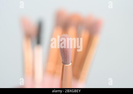 diversi pennelli rosa e oro per il trucco su sfondo chiaro Foto Stock