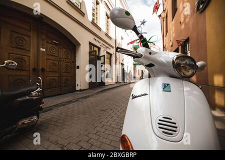 Uno scooter bianco in Vespa parcheggiato nella Città Vecchia di Vilnius, Lituania Foto Stock