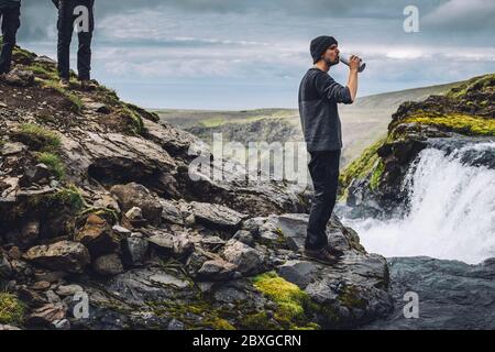 Uomo che beve acqua fresca da un fiume vicino Landmannalaugar, Fjallabak Riserva Naturale, Sud Centrale Islanda, Islanda Foto Stock