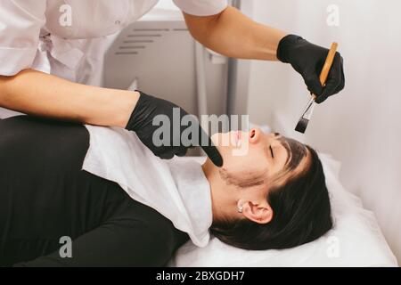 Estetista preparando una donna per un trattamento di bellezza con buccia di carbonio in una clinica Foto Stock