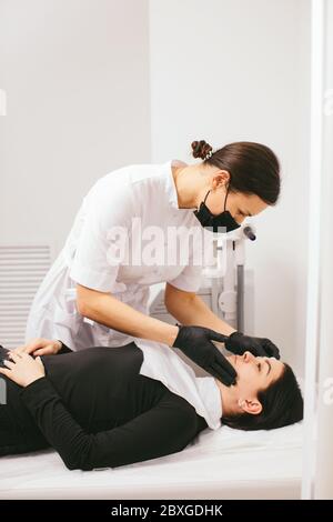 Estetista preparando una donna per un trattamento di bellezza con buccia di carbonio in una clinica Foto Stock