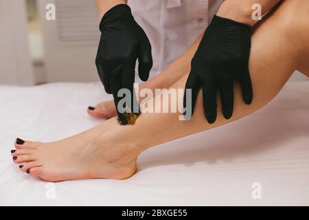 Donna che ha la gamba cerata in un salone di bellezza Foto Stock
