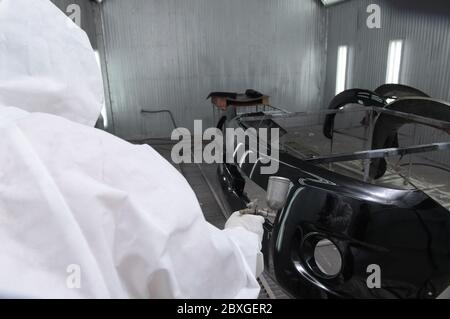 Vista posteriore di un meccanico che respira un'auto, Thailandia Foto Stock