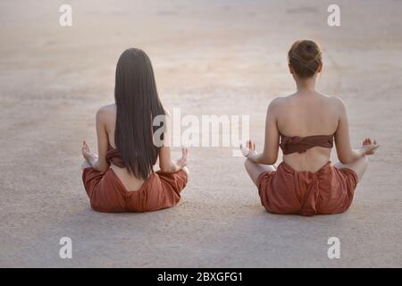 Vista posteriore di due donne che praticano yoga all'aperto, Thailandia Foto Stock