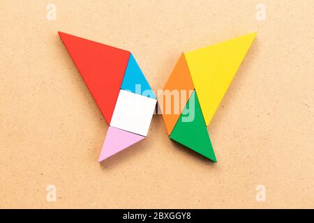 Puzzle tangram a forma di farfalla su bacground di legno Foto Stock