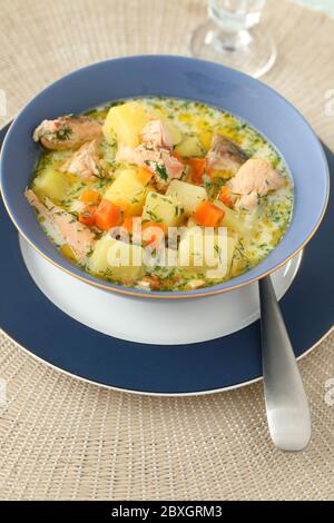 Zuppa di salmone cremosa finlandese Lohikeitto in una ciotola blu su un tavolo di festa Foto Stock