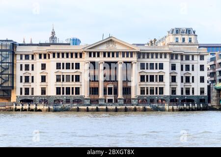 La classica facciata in granito e pietra calcarea lungo il fiume di Vintners si trova in Upper Thames Street, dall'altra parte del fiume Tamigi, Southwark, Londra, Regno Unito Foto Stock