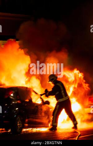 Fiamme e nuvole di fumo e vapore che si possono inzidire mentre un fuoco affronta una fiamma in un veicolo a motore di notte, adatto per una copertina di libro Foto Stock