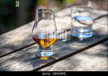 Degustazione di scotch single malt whisky dall'isola di Islay, il più intensamente aromatizzato di tutti i whisky in Scozia su vecchio tavolo da giardino in giornata di sole Foto Stock