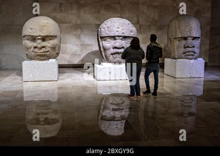 Visita turistica colossale teste di pietra Olmec al Museo di Antropologia nel centro storico di Xalapa, Veracruz, Messico. La civiltà Olmec fu la prima civiltà mesoamericana conosciuta, che risale approssimativamente dal 1500 a.C. a circa 400 a.C.. Foto Stock