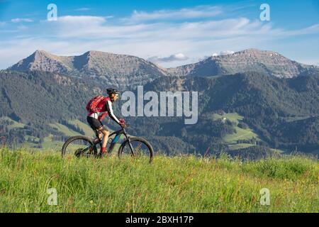 Bella donna anziana che cavalcava la sua mountain bike elettrica sopra Oberstaufen con una vista spettacolare sul Valdo di Bregenz, sulle Alpi di Allgau, in Baviera Germania Foto Stock