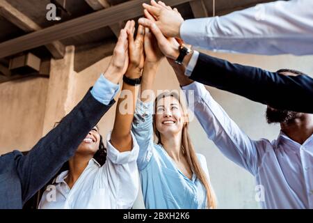 Gioioso team di collaboratori che si occupa di celebrare l'accordo in ufficio per i cinque grandi Foto Stock