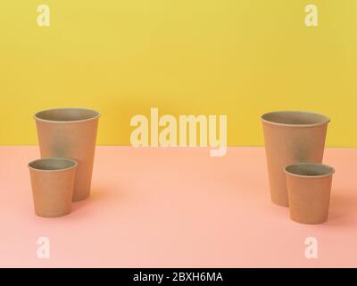 Utensili da cucina ecologici su sfondo rosa e giallo. Tazze di carta. Foto Stock