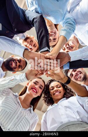 United Business Team di colleghi che hanno mani in mano, vista dal basso Foto Stock