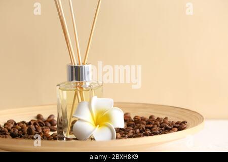 Piatto con diffusore a lamelle, chicchi di caffè e fiore sul tavolo Foto Stock