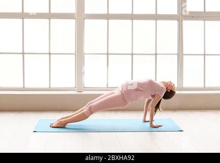 Giovane donna incinta che pratica yoga in palestra Foto Stock