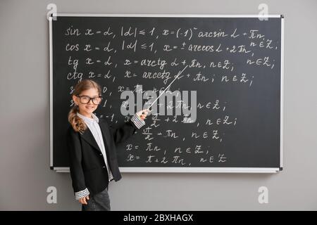 Carina piccola scolaretta vicino a lavagna in classe Foto Stock