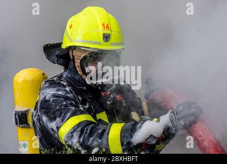 07 giugno 2020, Hessen, Francoforte sul meno: I vigili del fuoco combattono un incendio nel quartiere Preungesheim di Francoforte. L'incendio si era rotto in un complesso di magazzini per motivi ancora sconosciuti. Un pompiere con apparecchio di respirazione è in piedi nel mezzo di fumo spesso. Foto: Boris Roessler/dpa Foto Stock