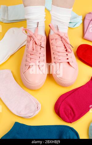 Piedi femminili in sneakers rosa e molti calzini in diversi colori. Tempo di vestiario Foto Stock