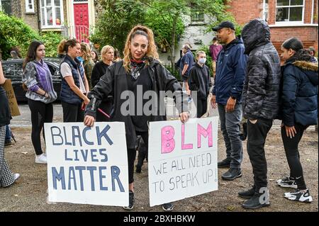 Donna mista con due cartelli "Black Lives Matter", "BLM abbiamo tutti bisogno di parlare in su" circondato da famiglia e amici in una dimostrazione. Londra. Foto Stock