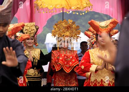Shy tradizionale Minangkabau ballerina donna guardando la folla, a Sumatra, Indonesia. Donne vestite con colorati abiti Minang in una cerimonia pubblica a Pad Foto Stock