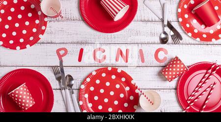 Piatti di carta monouso per un picnic con pois e strisce di polka rossa - piatti, tazze e posate. Vista dall'alto. Foto Stock