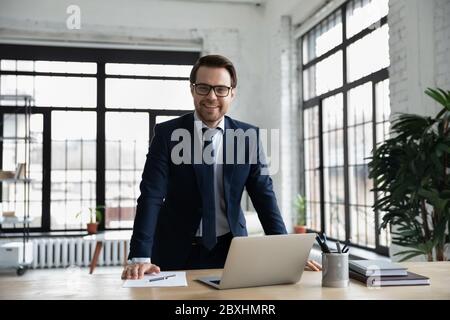 Ritratto di un uomo d'affari sorridente che posa sul posto di lavoro Foto Stock