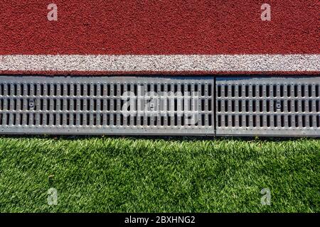 Il confine tra il campo di calcio e il tapis roulant nello stadio sportivo sotto forma di grondaia. Scarico dell'acqua nello stadio Foto Stock