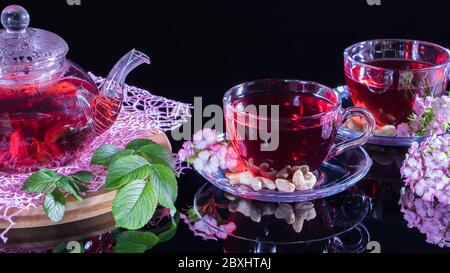 Tempo del tè: Tazza di tè. Layout creativo fatto di tazza di tè hibiscus e foglie. Tè rosso, carcade, karkade, rooibos. Orientale, accogliente, cerimonia, tradizione, Foto Stock