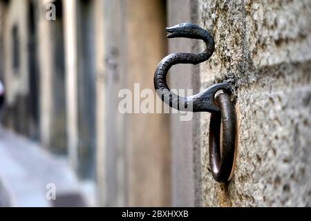 Anello da muro con sculture di serpente arrugginito per legare cavalli a Bergamo, Italia. Foto Stock