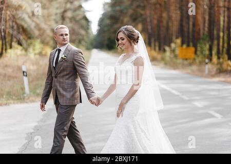 Sposi che si trovano sulla strada nella pineta. Ritratto di sposa e sposo Foto Stock