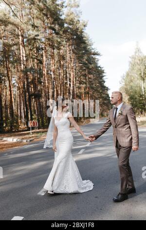 Sposa e sposo che si trova sulla strada tra i pini. Ritratto di sposa e sposo Foto Stock