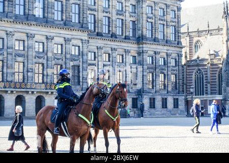 Polizia a cavallo nella tranquilla Amsterdam (Paesi Bassi) durante la crisi del Covid-19, vista della vuota piazza Dam Foto Stock