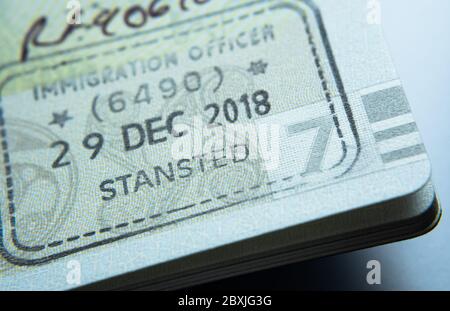 Timbro di ingresso sul passaporto rilasciato dall'agente dell'immigrazione alla frontiera e controllo dei visti all'aeroporto di Stansted nel Regno Unito. Messa a fuoco selettiva. Foto macro. Foto Stock