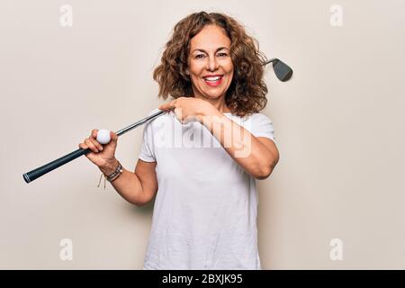 Media età bella sportivo che gioca a golf usando bastone e palla su sfondo bianco sorridente felice puntando con mano e dito Foto Stock