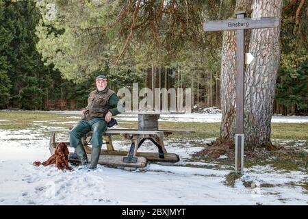 Un escursionista e il suo cane si riposano al Binsberg, una meta popolare per escursioni e escursioni sull'Alb Svevo in Germania. Foto Stock