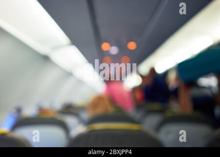 Passeggeri e equipaggio seduti sui sedili dell'aereo, vista dei passeggeri e degli assistenti all'interno della cabina Foto Stock